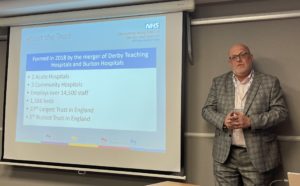 A photograph of Mark Chester, Head of Digital Technology at University Hospitals of Derby and Burton NHS Foundation Trust co-presenting with BridgeHead Software at the MEDITECH User Network (MUN) 2022 event in Liverpool