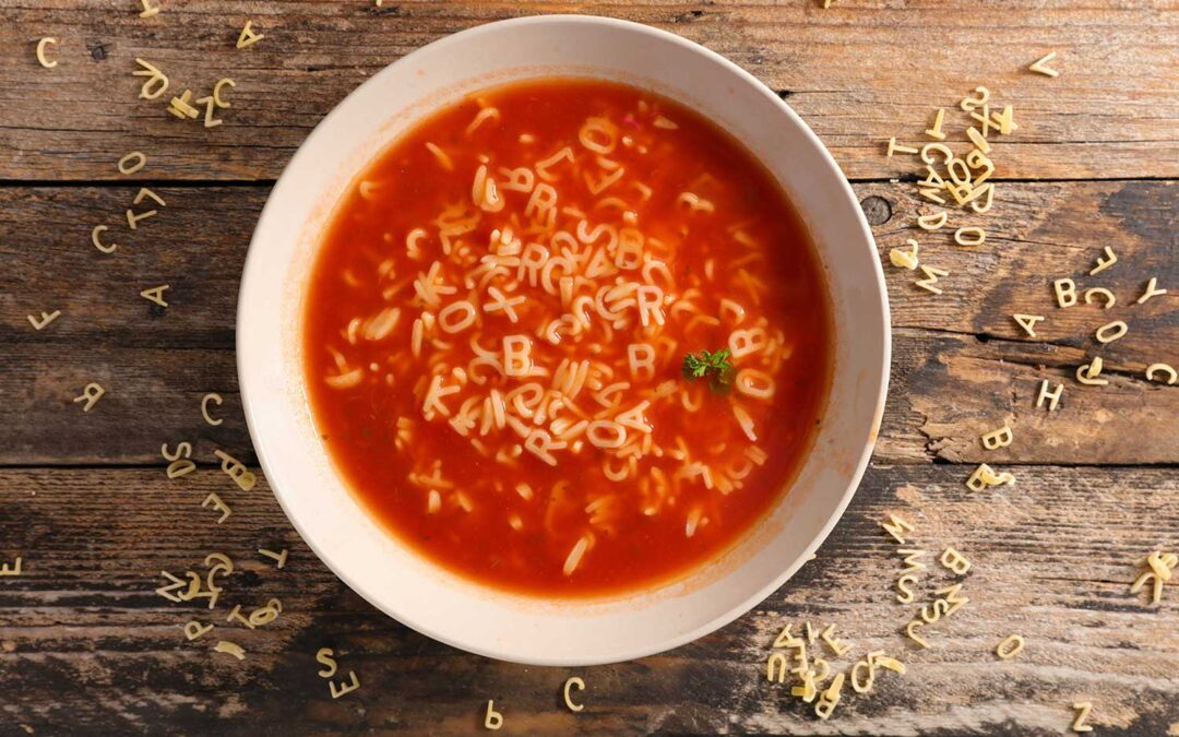 Bowl of red soup containing spaghetti letters