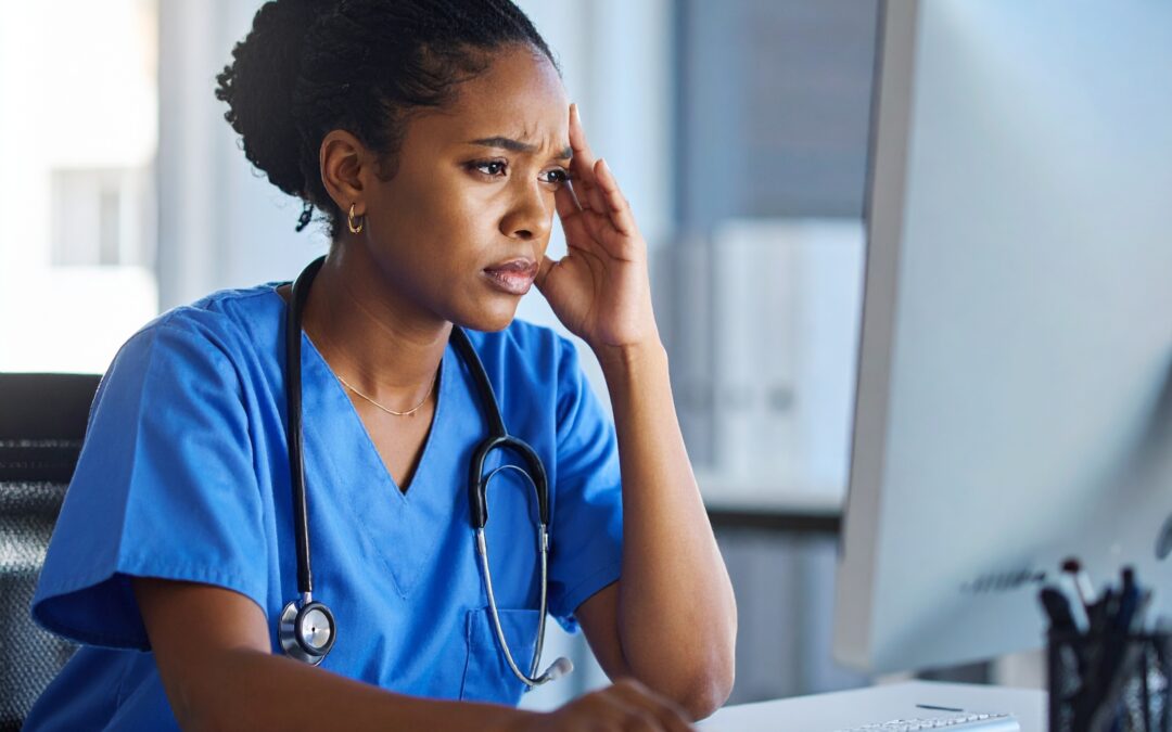 An image of a frustrated NHS nurse in front of a computer because she can't find the data she is looking for